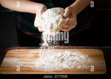 Il processo di preparazione della pasta per pizza, le mani femminili impastano la farina Foto Stock