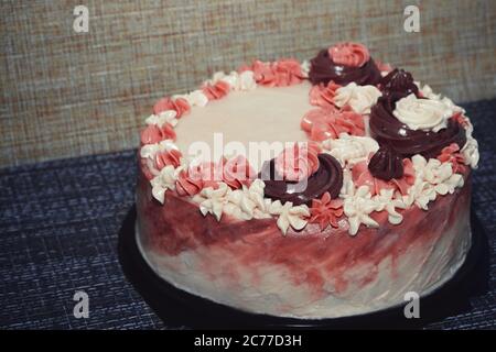 Torta di compleanno rosa con fiori di crema su sfondo scuro Foto Stock