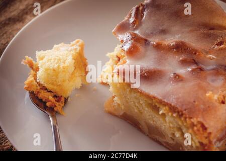 Fetta di torta fatta in casa di mele su un cucchiaio da vicino su uno sfondo marrone Foto Stock
