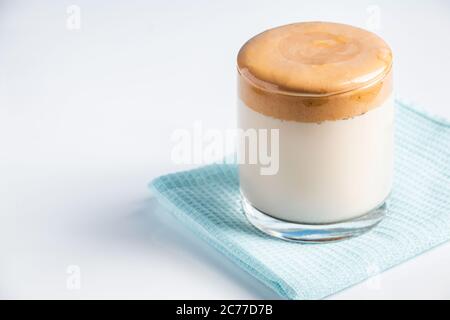 Caffè Dalgona isolato su sfondo bianco. Bevanda alla moda fatta di latte e schiuma montata dolce. Foto Stock