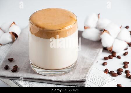 Caffè dalgona ghiacciato. Un bicchiere di bevanda alla moda soffice fatta di latte e panna montata su uno sfondo grigio. Foto Stock