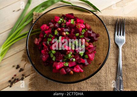 Vinaigrette su sfondo ligneo. Insalata russa di verdure con barbabietole rosse in un recipiente. Stile rustico, piatto tradizionale. Foto Stock