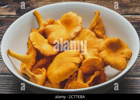 Funghi porcini arancioni selvatici in un piatto bianco su fondo marrone. Foto Stock