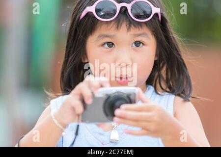 Carina bambina con fotocamera digitale compatta si sente sorprendente con la sua ripresa in viaggio in Thailandia Foto Stock