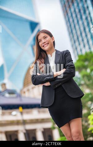 Donna di affari ritratto fiducioso a Hong Kong. Donna d'affari in piedi orgogliosa e riuscita in tuta cross-armato. Giovane multirazziale cinese asiatico Foto Stock