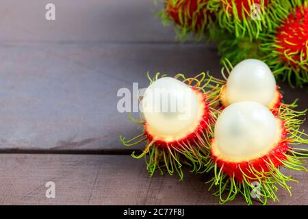 Rambutan fresco sbucciato su tavolo di legno con mazzo di fresco rambutan matura sfondo. Frutta tropicale fresca rambutan sbucciato Foto Stock