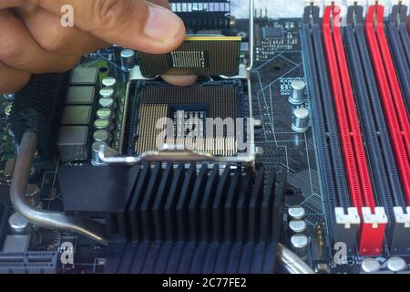 Primo piano del tecnico che mette la CPU sullo zoccolo della scheda madre del computer Foto Stock