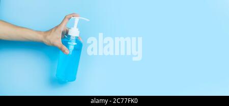 Gel di alcol per la mano. Igienizzatore a gel di alcol per la mano. Donne mani che tengono l'igienizzatore in gel di alcol nel flacone con testina a pompetta su sfondo azzurro . Foto Stock