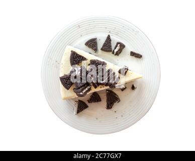Vista dall'alto cheesecake fatto in casa senza freni con biscotti al cioccolato e crema su piatto. Isolare su panettonati bianchi Foto Stock