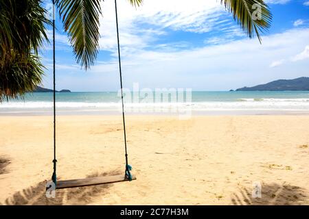 Concetto estivo. Altalena di legno appesa alla palma di cocco sul mare della spiaggia. Asia Thailandia. Con spazio di copia per testo o disegno Foto Stock