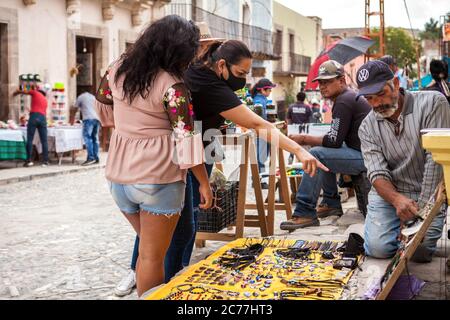 Real De Catorce, Messico. 28 Giugno 2020. I turisti che indossano maschere facciali sono visti acquistare oggetti artigianali da un artigiano sulla strada.la ''˜nuova normalità' in Messico ha iniziato all'inizio di giugno con la fine del blocco. I primi posti ad essere aperti al turismo sono stati Real de Catorce in San Luis PotosÃ- Stato. Anche se il numero di visitatori non è paragonabile a quello precedente alla pandemia di Covid-19, ha iniziato lentamente a riavviare l'economia, soprattutto dove il turismo è la principale fonte di reddito. Credit: Antonio Cascio/SOPA Images/ZUMA Wire/Alamy Live News Foto Stock