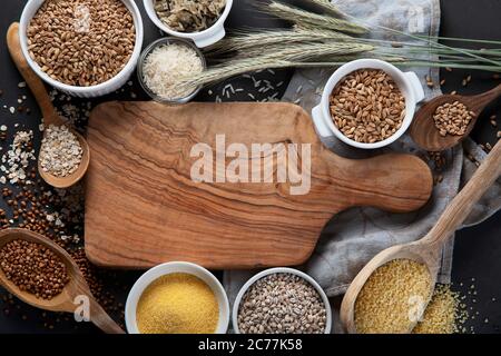 Diversi tipi di cereali in ciotole su fondo nero. Alimentazione sana. Vista dall'alto. Foto Stock