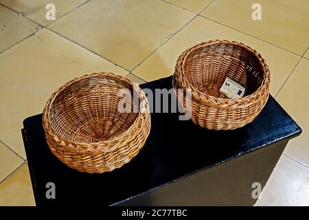 Due cesti di wisker con un solo conto di 5 euro in una chiesa Foto Stock