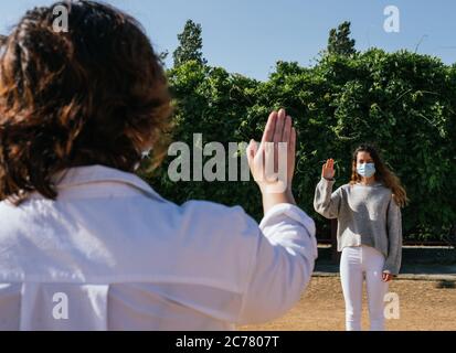 Distanza sociale. Due vicini camminano attraverso un parco e si salutano mentre mantengono una distanza sicura. Parlare con più di un inserto protettivo. P Foto Stock