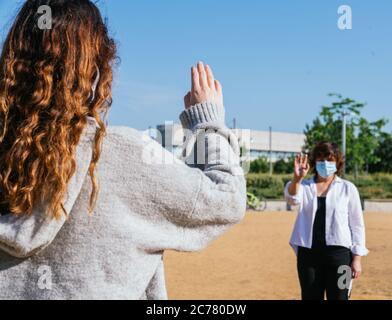 Distanza sociale. Due vicini camminano attraverso un parco e si salutano mentre mantengono la loro distanza dalla pandemia. Pandemia. Dev. Virus coronazione Foto Stock