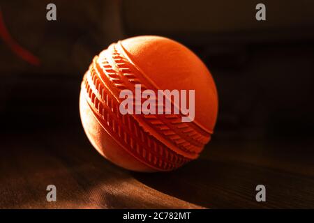 una sfera di gomma rotonda di colore rosso isolata su un tavolo di tessitura in legno Foto Stock
