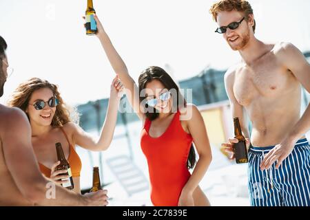 Giovani in costume da bagno che hanno tempo a bere birra, sentirsi eccitati Foto Stock