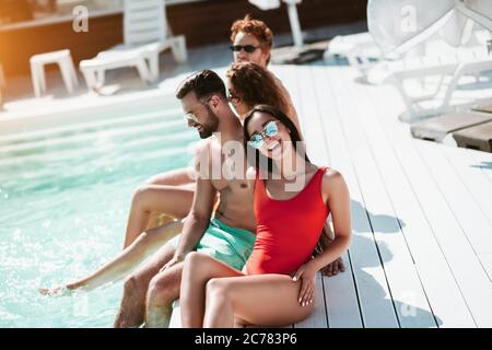 I giovani seduti vicino alla piscina si prendono il sole e si sentono impressionanti Foto Stock