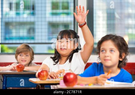 Scena scolastica elementare. Compagni di classe multietnici in classe. Foto Stock