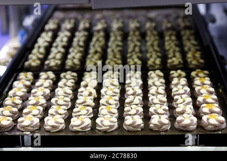 La linea di produzione di biscotti con marmellata bicolore lascia cadere i biscotti sui vassoi. Messa a fuoco selettiva. Foto Stock