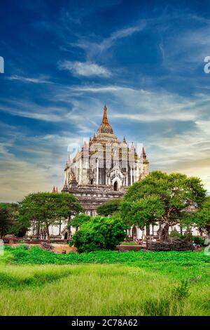 Una grande pagoda antica con uno stile d'arte birmano che si trova nel mezzo di un campo verde nella zona del Patrimonio Mondiale dell'Umanità di Myanmar. Foto Stock