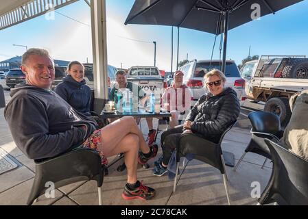 Un gruppo di persone si siede sorridendo in una mattinata invernale a un tavolo all'aperto vicino a una caffetteria a Mudgee, New South Wales, Australia Foto Stock