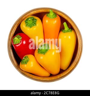 Peperoni colorati in ciotola di legno. Anche peperone dolce o capsicum. Frutti freschi di Capsicum annuum, di colore giallo, arancio e rosso. Foto Stock