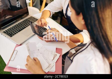 I proprietari di caffè giovani controllano le fatture e i controlli di paga quando calcolano i redditi e le spese Foto Stock