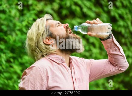 Calore estivo. Acqua potabile. Equilibrio dell'acqua. Uomo sopportato turista acqua potabile bottiglia di plastica natura sfondo. Ragazzo assetato che beve acqua in bottiglia. Stile di vita sano. Sicurezza e salute. Foto Stock