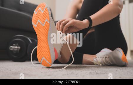 Donna che lega i calzoloni prima dell'esercizio. Concetto di allenamento domestico per il fitness. Foto Stock