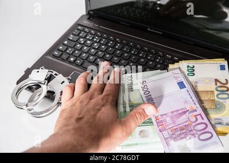 Bamberg, Germania 13 luglio 2020: Immagini simboliche - 2020 diverse migliaia di euro in contanti con il valore di 500 euro, 200 euro, 100 euro e 50 euro si trovano su un portatile con manette, cibercriminalità, cibercriminalità, | utilizzo in tutto il mondo Foto Stock