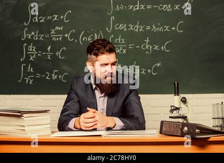 Hipster scuola. Hipster insegnante. Hipster in classe. Uomo Barbuto in convenzionale a tabella insegnanti. Uomo brutale in hipster stile nella scuola o università. Foto Stock