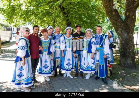 Riga, Lettonia - 9 luglio 2018: Ritratto di gruppo della squadra amatoriale del folclore bielorusso in costumi nazionali e due ragazzi pakistani al tradizionale all Foto Stock