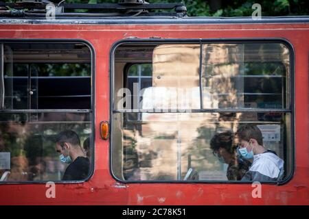 BELGRADO, SERBIA - 8 LUGLIO 2020: Giovane uomo alla finestra di un tram che indossa una maschera respiratoria viso nei mezzi pubblici di Belgrado, durante il decor Foto Stock