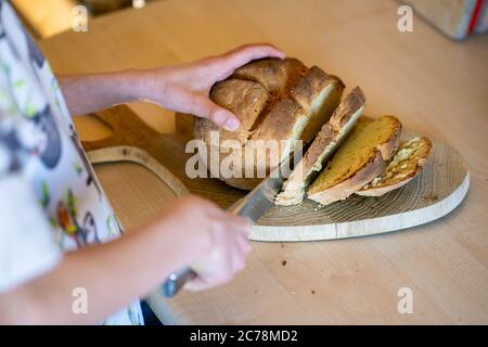 Pane di soda irlandese appena sfornato, con croce tagliata a fette da giovane ragazza. Pasticceria sana, fatta in casa, deliziosa. Foto Stock