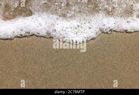 Primo piano Vista di una piccola onda liscia su una spiaggia in serata per sfondo Foto Stock