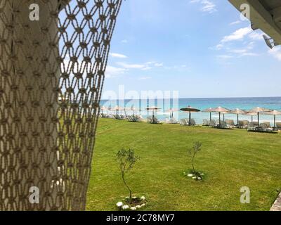 Vista mare e vista di alcuni sdraio e ombrelloni sulla spiaggia, ora estiva Foto Stock