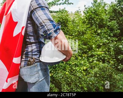 Bell'uomo con gli attrezzi, che tiene una bandiera canadese Foto Stock