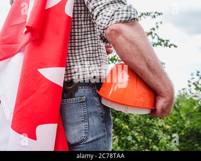 Bell'uomo con gli attrezzi, che tiene una bandiera canadese Foto Stock