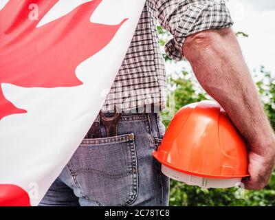 Bell'uomo con gli attrezzi, che tiene una bandiera canadese Foto Stock