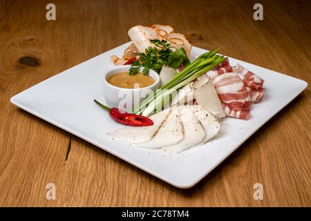 Assortimento di carne: Affettare carne e lardo con senape, cipolle verdi ed erbe. Maiale, manzo e pancetta. Foto Stock