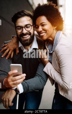 Imprenditori felici che utilizzano dispositivi tecnologici gadget vicino alla parete di un edificio moderno Foto Stock