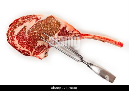 Età secco materie tomahawk bistecca isolati su sfondo bianco, vista frontale, close-up con una forcella di carne Foto Stock