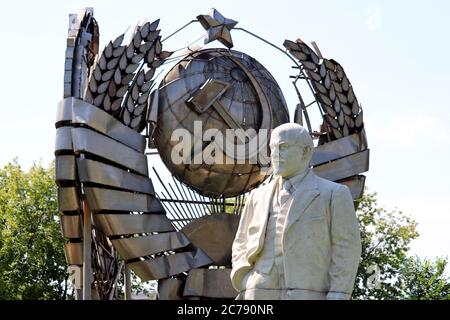 Monumento a Lenin, il leader del proletariato russo contro lo stemma dell'URSS nel parco estivo Foto Stock