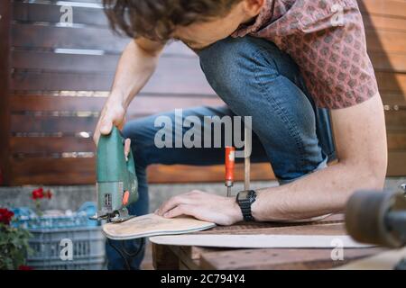 Uomo tagliato con sega elettrica mentre si fa skateboard Foto Stock