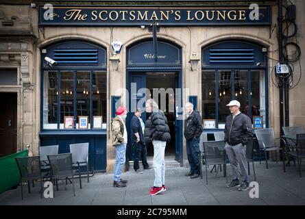 La gente aspetta di aprire fuori del pub Scotsman's Lounge di Edimburgo, poiché pub, bar e ristoranti in tutta la Scozia hanno aperto aree interne per la prima volta da marzo dopo l'abolizione di ulteriori restrizioni di blocco del coronavirus. Foto Stock