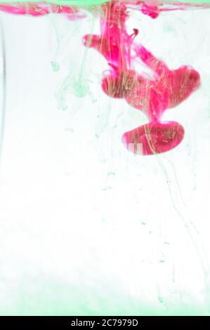 Una fotografia closeup di colore rosa e verde mescolato in acqua. Foto Stock