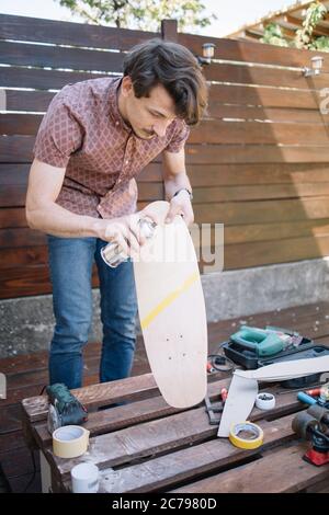 Skateboard per la presa di persone concentrate mentre lo dipingi all'aperto Foto Stock