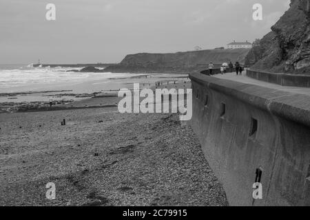 Immagine monocromatica della passeggiata lungo il bordo sia della spiaggia e scogliera in un giorno ventoso e piovoso in estate a Seaham nella contea di Durham Foto Stock