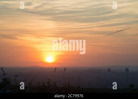 Immagine del tramonto sul campo da cricket della contea di Durham a Chester-le-Street con i riflettori e il campanile della chiesa parrocchiale in silhouette Foto Stock
